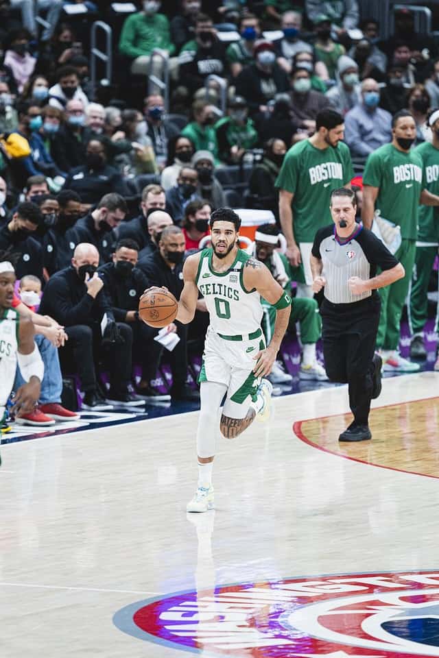 Foto de archivo: Jayson Tatum, con la camiseta blanca número 0 de los Celtics, avanza con la pelota en la mano y el banco de Boston detrás
