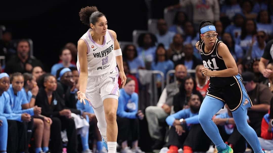 Janelle Salaun, de las Valkyries, con la camiseta blanca número 13, corre la cancha seguida por una jugadora del Dream, de negro y celeste, con hinchas de Atlanta de fondo