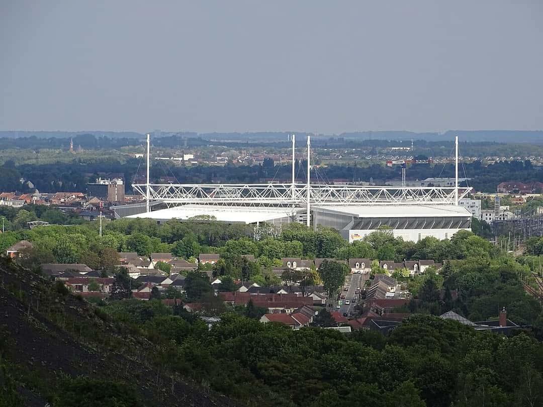El estadio Bollaert-Delelis visto desde lo alto de una colina, con su techo blanco y las casas de Lens alrededor; foto de archivo de 2020 (foto: Adrelaxen, Wikimedia Commons, licencia CC BY-SA 4.0)