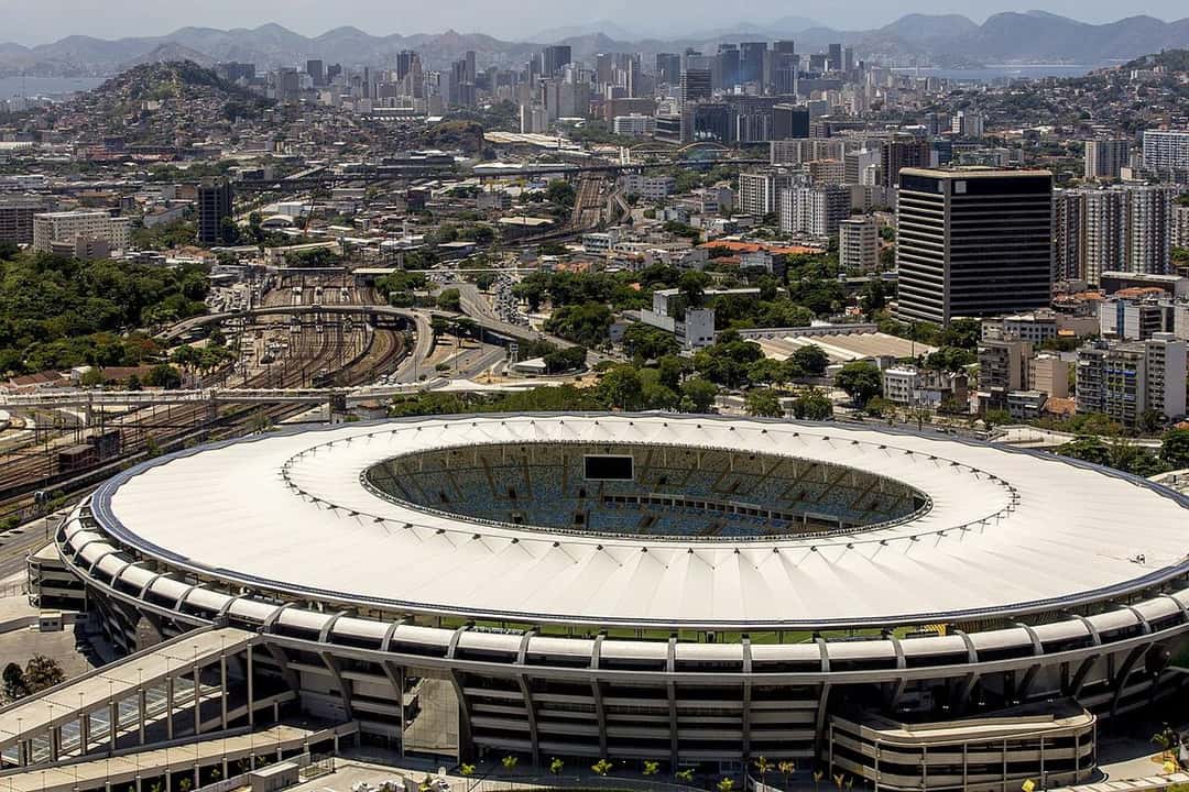 Vista aérea del estadio Maracaná, en Río de Janeiro, con su techo blanco y la ciudad de fondo; foto de archivo de 2014 (foto: Daniel Basil, Wikimedia Commons, licencia CC BY 3.0 BR)