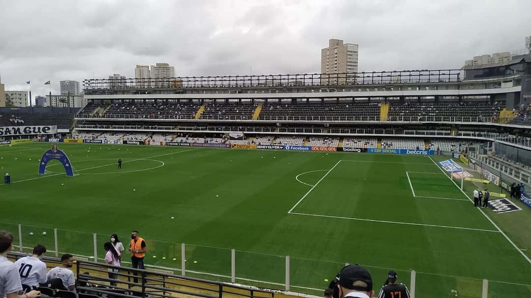 La cancha de la Vila Belmiro vista desde la tribuna antes de un partido del Santos, con las plateas blancas y negras de fondo; foto de archivo de 2021 (foto: BrazilianDude70, Wikimedia Commons, licencia CC BY-SA 4.0)