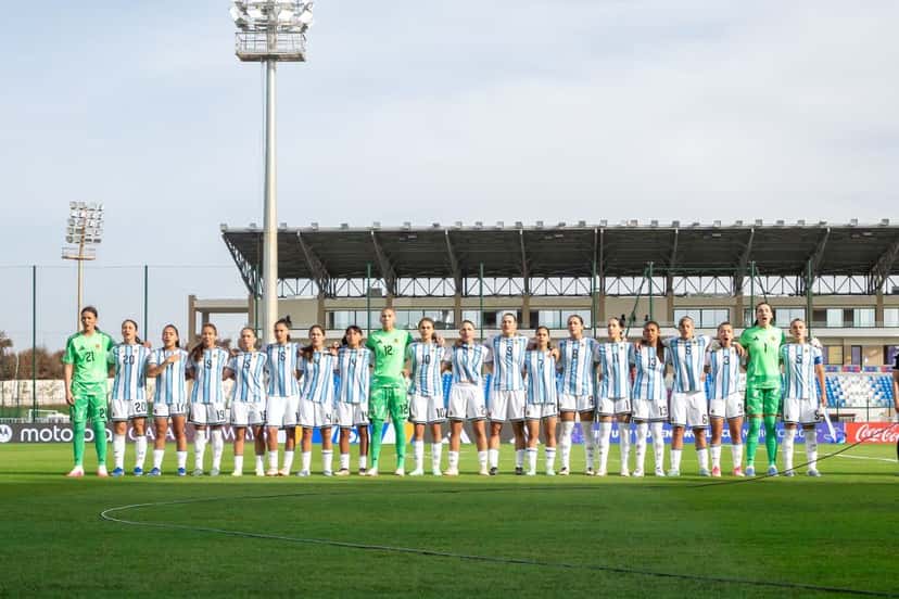 Las jugadoras de la Selección argentina femenina Sub-17, con la camiseta celeste y blanca, y las arqueras de verde, formadas en la cancha durante los himnos antes de un partido del Mundial de Marruecos (foto: prensa AFA)