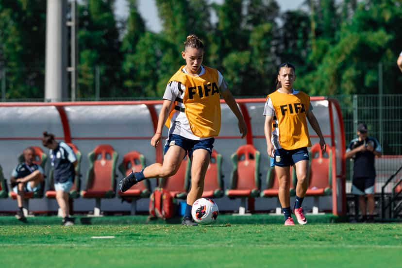 Dos jugadoras de la Selección argentina femenina Sub-17, con pecheras naranjas de la FIFA, manejan la pelota durante una práctica en Rabat (foto: prensa oficial de la AFA)