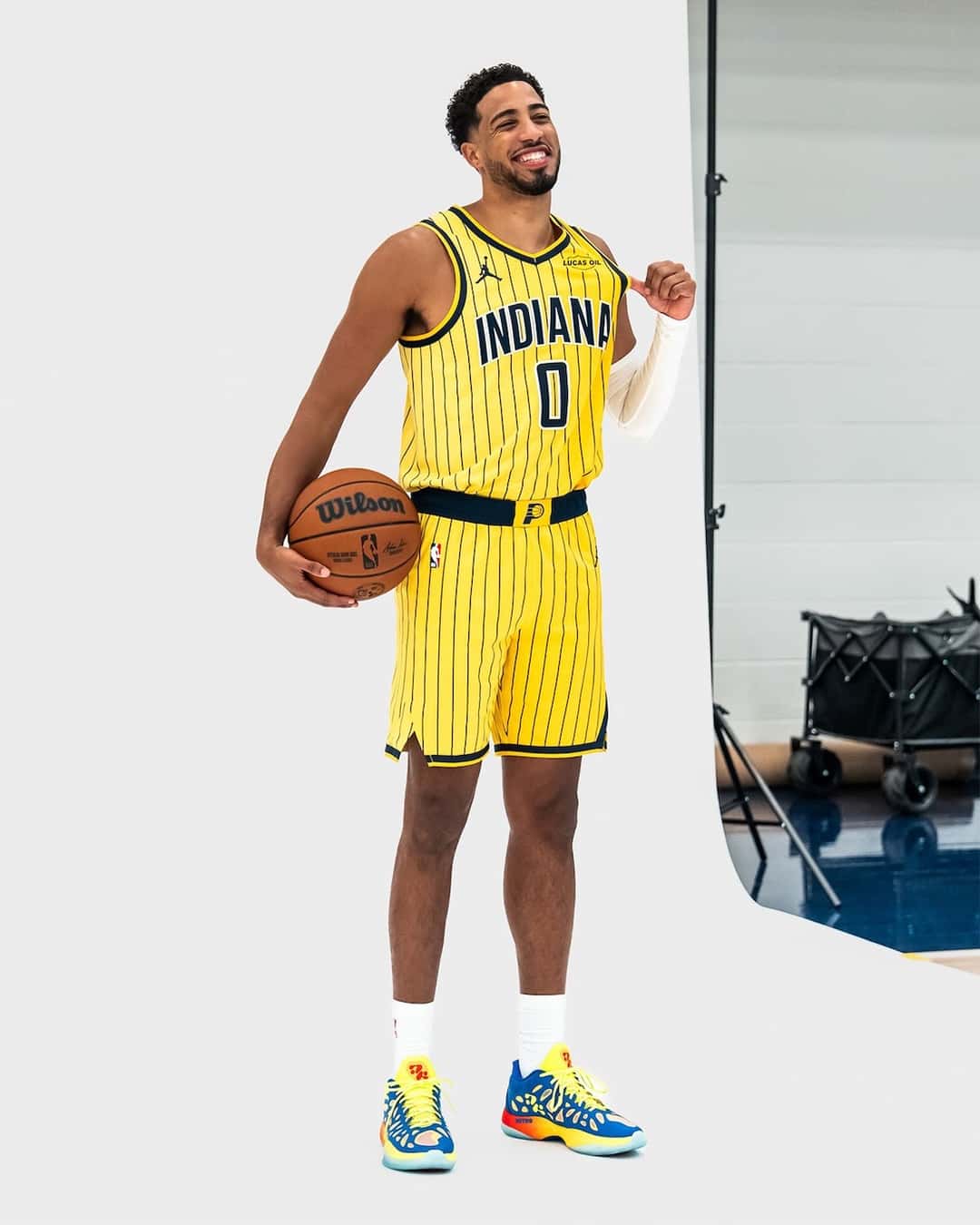 Tyrese Haliburton parado de frente con la camiseta amarilla de los Indiana Pacers número 0 y una pelota bajo el brazo, con las PUMA Hali 2 Thermal Vision puestas