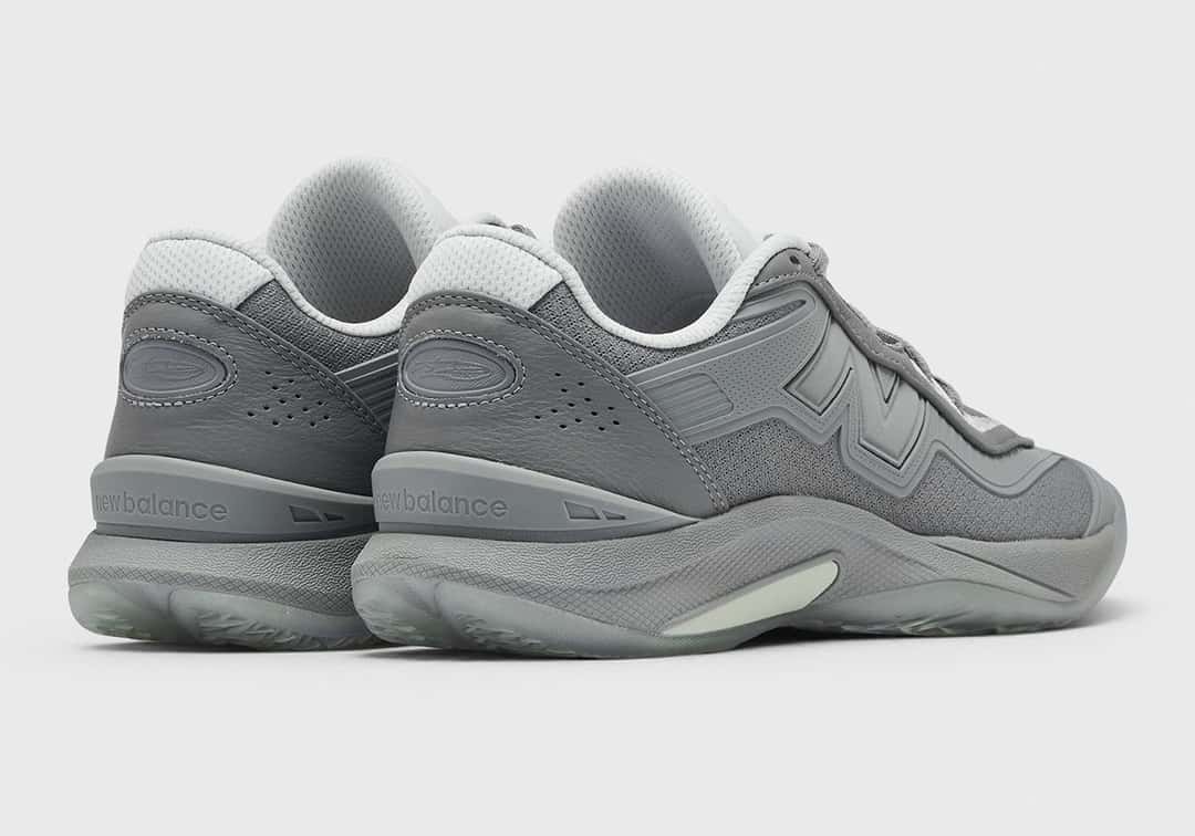 Par de New Balance Kawhi 5 Slate Grey visto desde atrás y de costado sobre fondo gris claro, con el logo New Balance en el talón