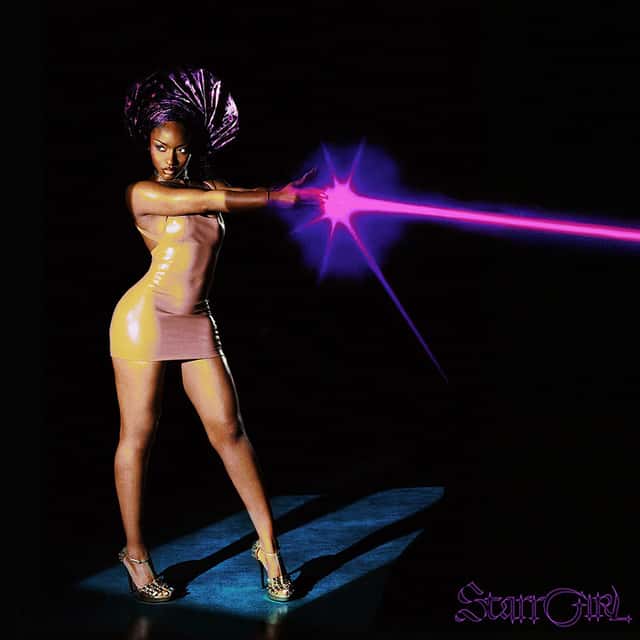 Portada oficial de «Starrgirl», de Ayra Starr: la cantante, con vestido dorado brillante y tocado violeta, apunta con el brazo extendido del que sale un rayo de luz rosa, sobre fondo negro