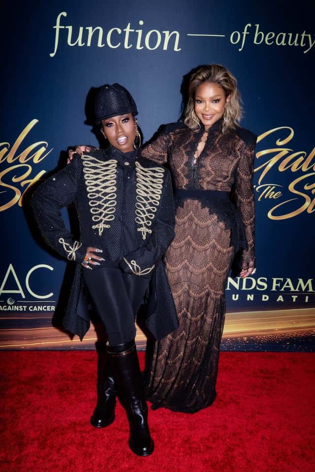 Missy Elliott, con gorra y chaqueta negras con bordados dorados y botas altas, posa abrazada con Janet Jackson, de vestido largo de encaje, en la alfombra roja de la Gala of the Stars. Foto: Derek Blanks / Dancers Against Cancer