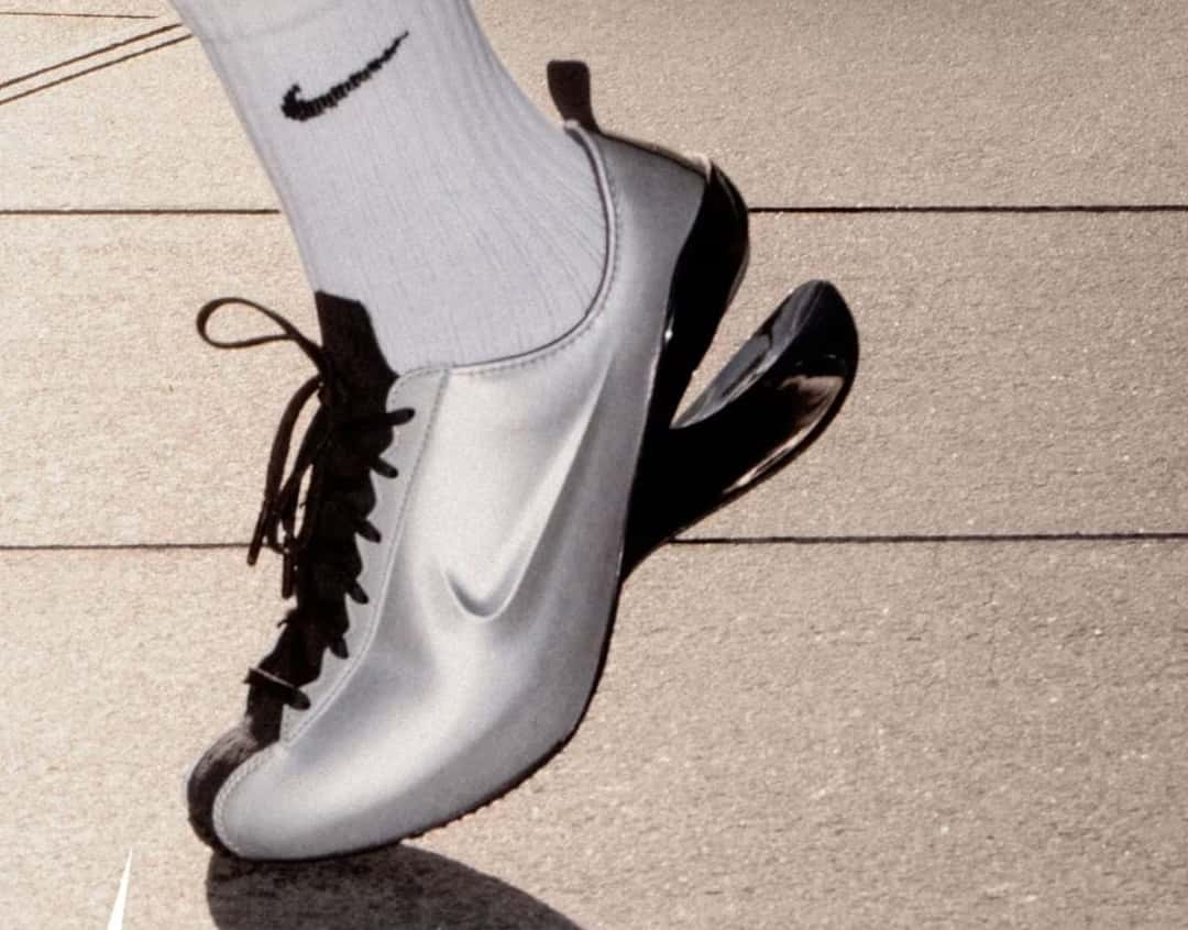 Nike Ovolo 2.0 plateada puesta con media blanca de Nike, vista de costado, con el taco negro separado de la base