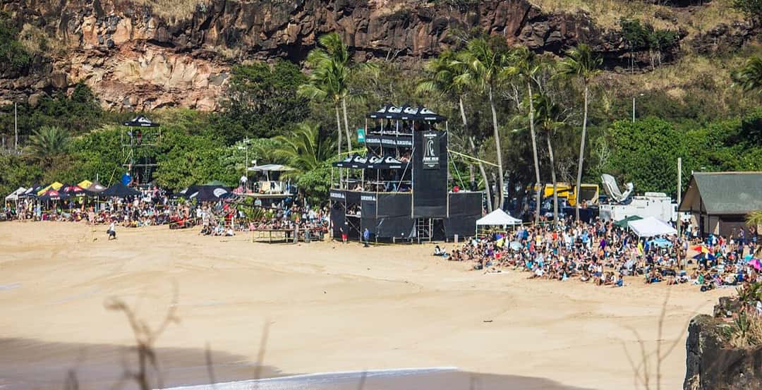 Una multitud mira el torneo desde la arena de Waimea Bay, con la torre de jueces y las carpas al pie del acantilado, en The Eddie de 2016 (foto de archivo)