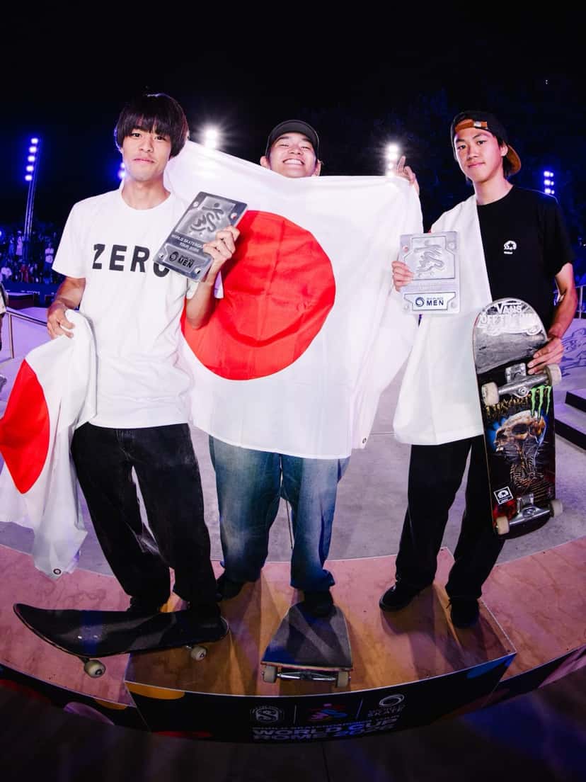 Kairi Netsuke, con una remera blanca de Zero y la bandera de Japón, en el podio de Roma junto a Sora Shirai y Toa Sasaki (foto de archivo)