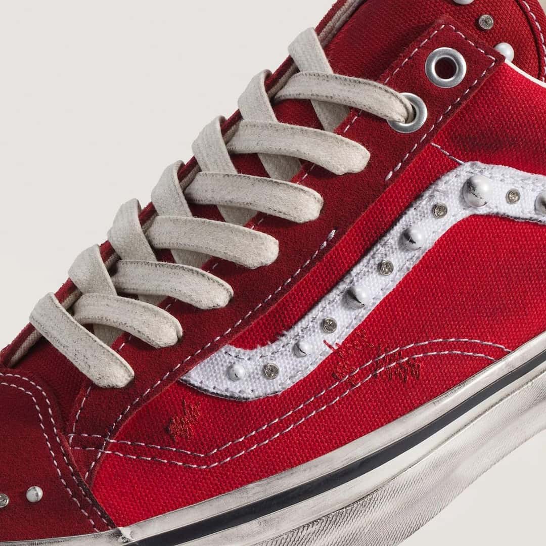 Detalle de la Vans Old Skool 36 Pearlized roja con cordones crema, ojal plateado y perlas sobre la franja lateral