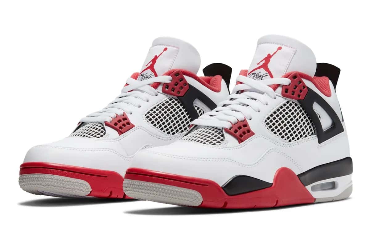 Foto de archivo: par del Air Jordan 4 Fire Red de 2020 en diagonal sobre fondo blanco, con upper de cuero blanco, ojales rojos, alas negras, malla blanca y negra, Jumpman rojo con la palabra Flight en la lengüeta, forro rojo y mediasuela roja y negra con suela gris