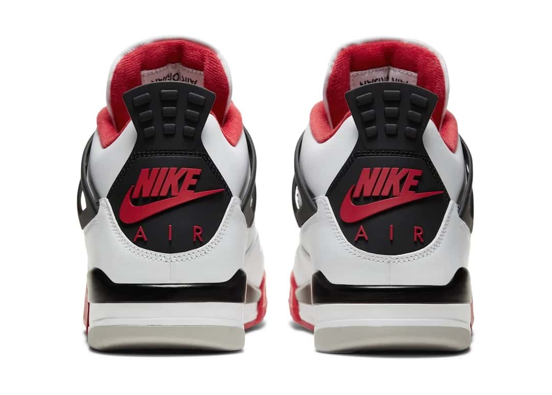 Foto de archivo: vista trasera del par de Air Jordan 4 Fire Red de 2020 sobre fondo blanco, con la pieza del talón negra, el logo Nike con swoosh y la palabra AIR en rojo, el forro rojo, la mediasuela negra y blanca y la suela gris