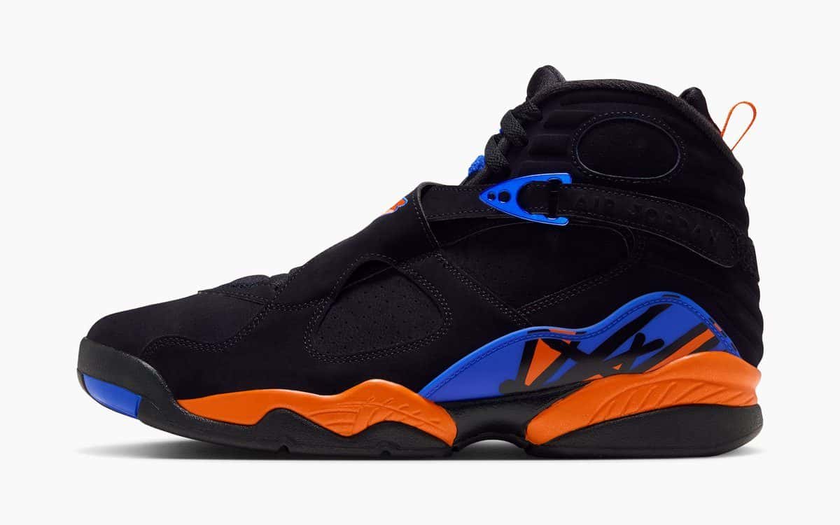 Air Jordan 8 Knicks de perfil en negro, con entresuela naranja, detalles en azul y las tiras cruzadas sobre el empeine, sobre fondo blanco