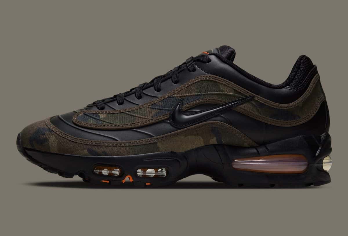 Nike Air Max Joga Bonito Camo de perfil sobre fondo gris topo, con piezas de camuflaje woodland sobre cuero negro y la cámara de aire con naranja