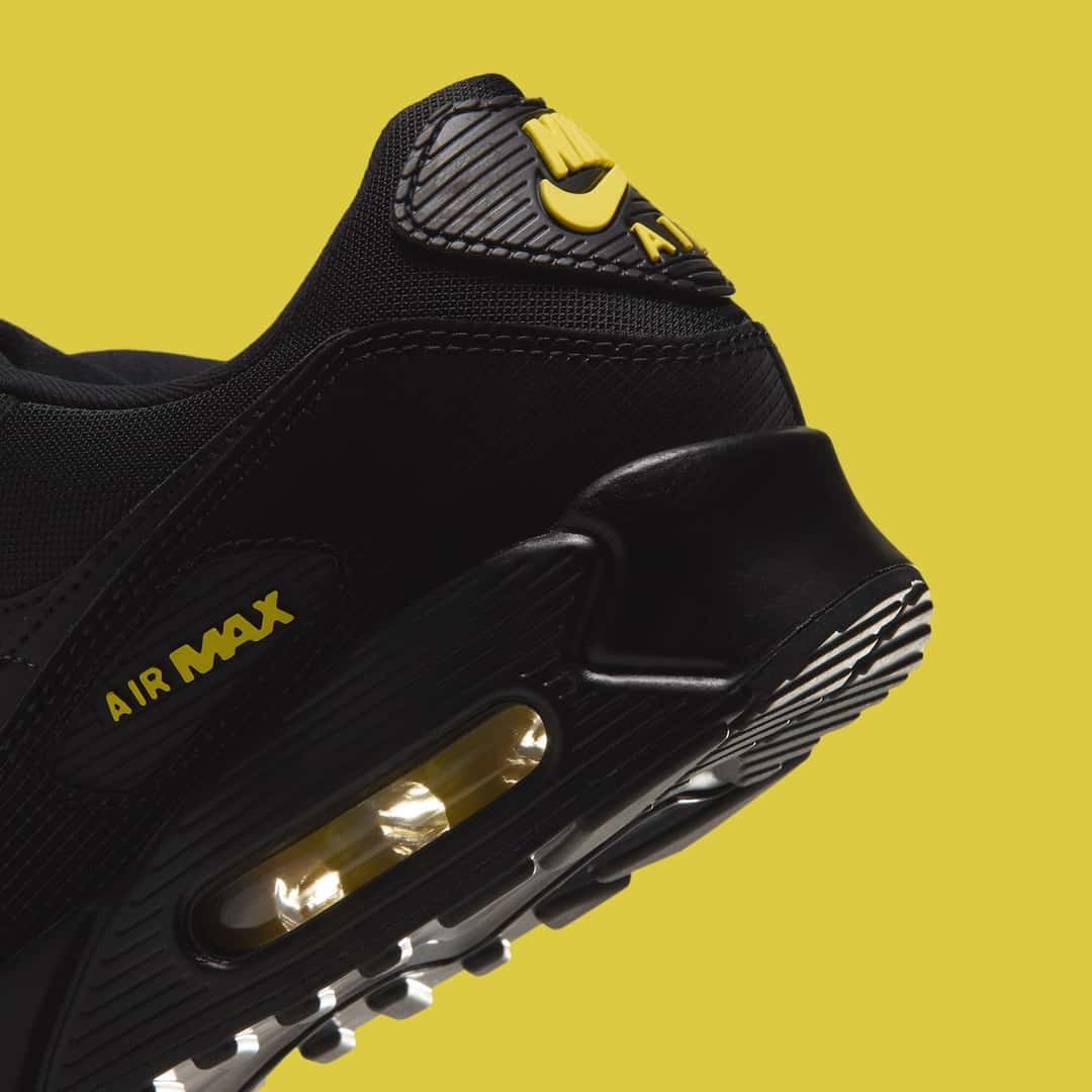 Detalle del talón de la Nike Air Max 90 del pack Batman sobre fondo amarillo, negra con la cámara de aire amarilla y el logo Air Max en amarillo