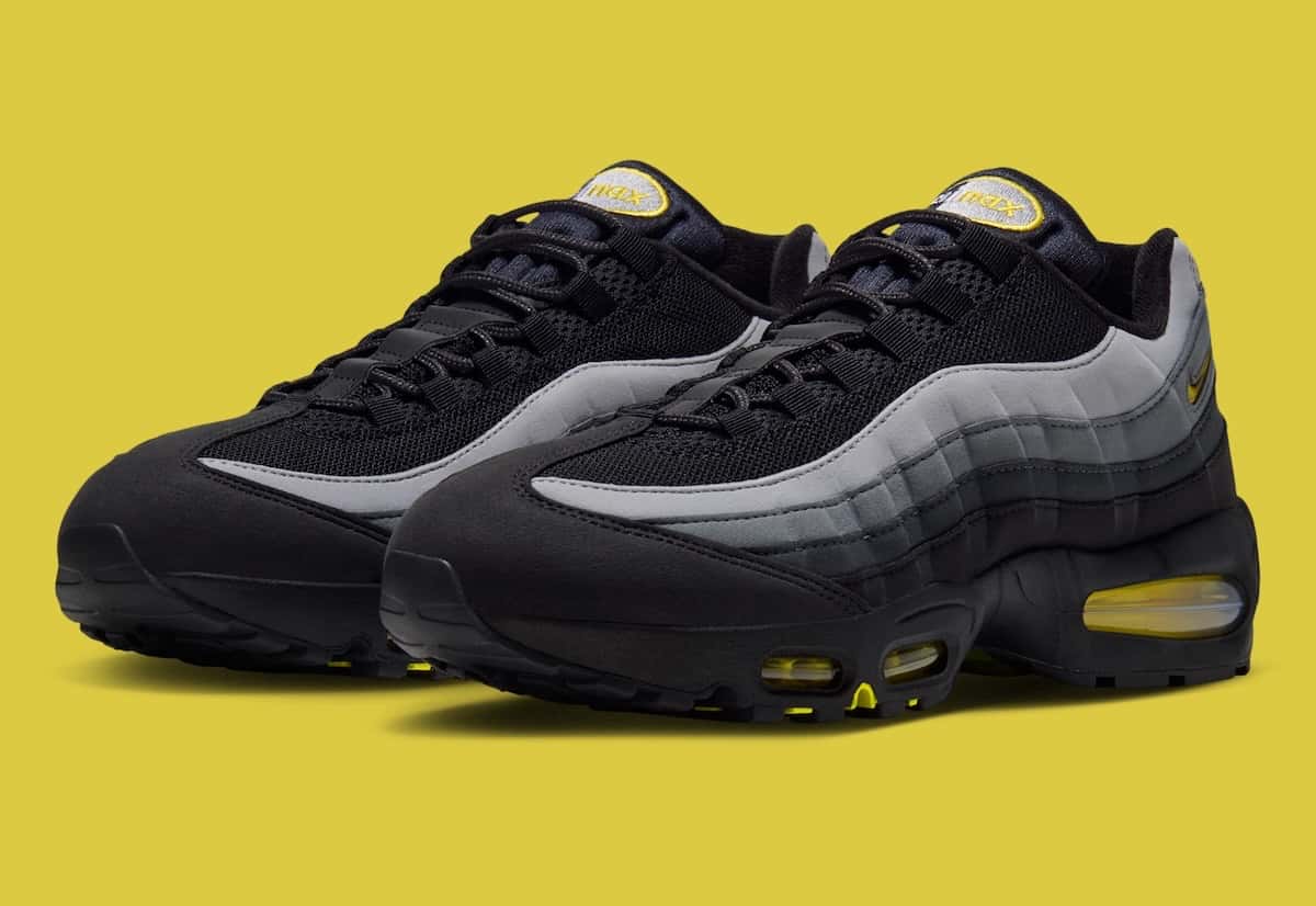 Par de Nike Air Max 95 negras con laterales en degradé gris y la cámara de aire amarilla, sobre fondo amarillo