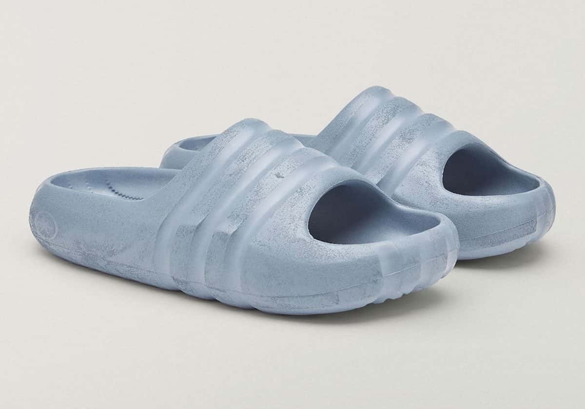 Par de ojotas Bad Bunny x adidas BadBo Stone Slides azul grisáceo, de una sola pieza, con las tres franjas talladas y una superficie que imita la piedra