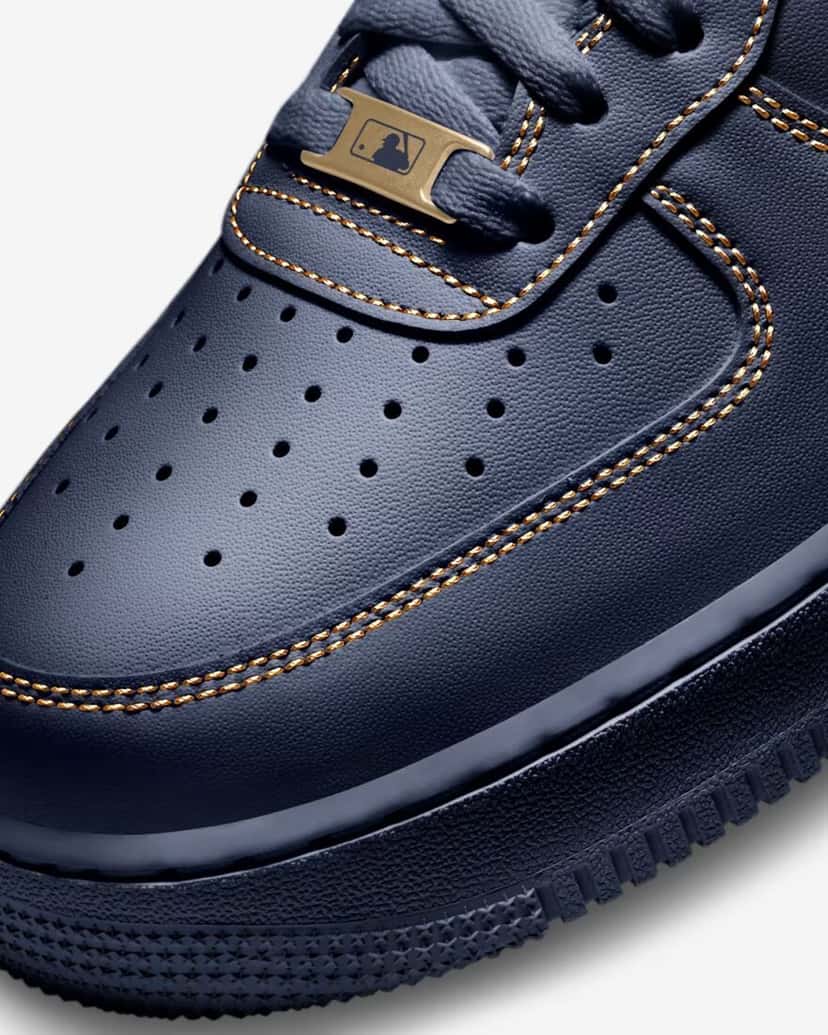 Detalle de la puntera de la Nike Air Force 1 Low Milwaukee Brewers, con el cuero azul marino perforado, las costuras doradas y la placa de la MLB en los cordones