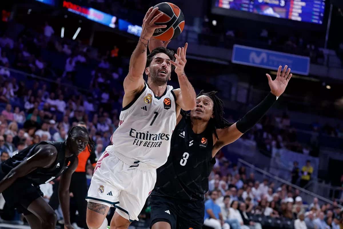 Facundo Campazzo, con la camiseta blanca número 7 del Real Madrid, salta hacia el aro con la pelota en la mano derecha ante la marca de un jugador del ASVEL de camiseta negra, en el Movistar Arena