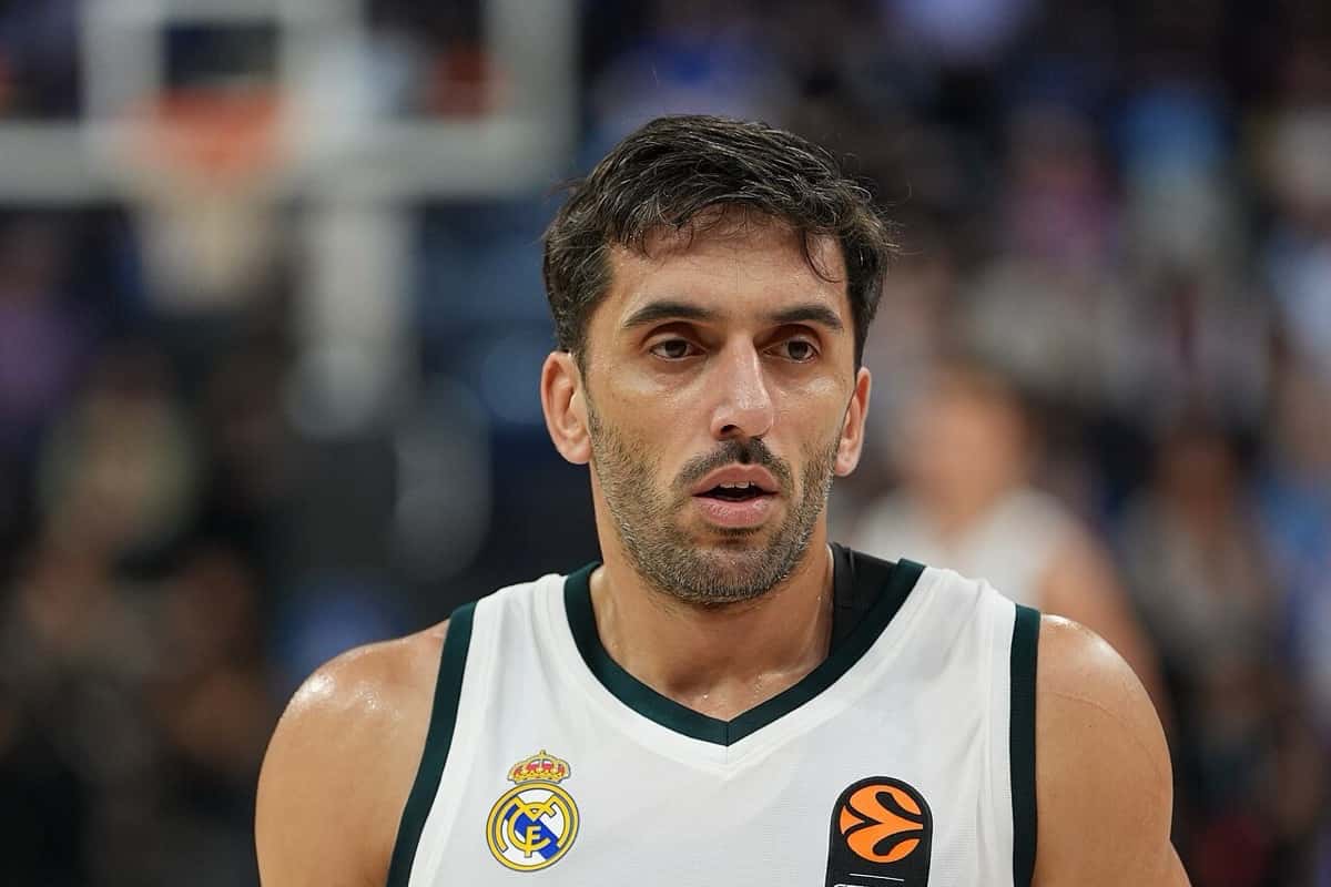 Foto de archivo: Facundo Campazzo, con la camiseta blanca del Real Madrid y el escudo del club en el pecho, mira hacia adelante durante un partido de Euroliga, con el aro y el público desenfocados detrás