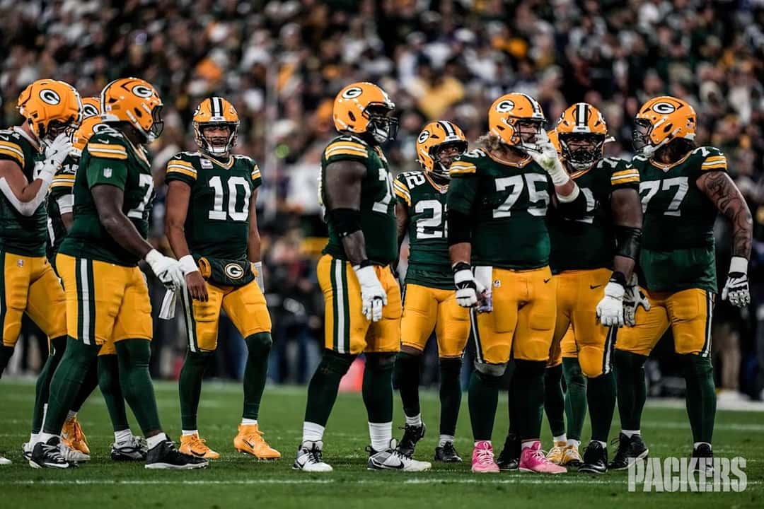 Jordan Love, con la camiseta verde número 10 de los Packers, en el medio del grupo de la línea ofensiva antes de una jugada en Lambeau Field