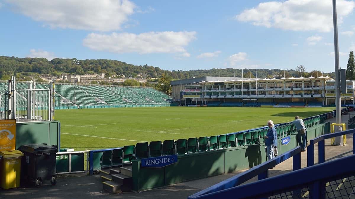 Foto de archivo: el Recreation Ground de Bath en un día de sol, con la tribuna principal blanca al fondo, las butacas verdes y la cancha vacía