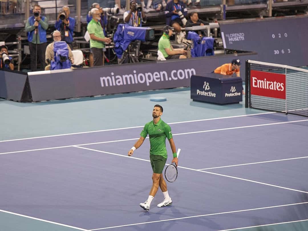 Foto de archivo: Novak Djokovic, con remera verde y short oscuro, camina por la cancha azul del Abierto de Miami en 2025