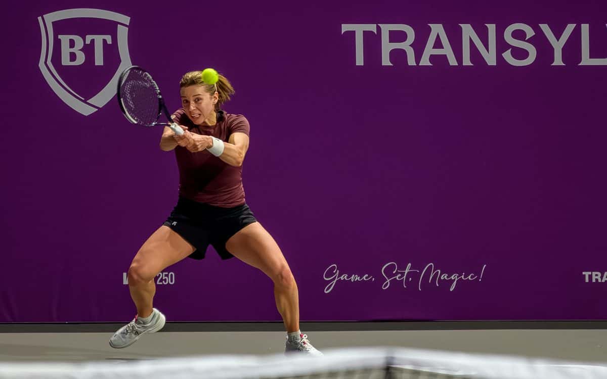 Foto de archivo: Maja Chwalinska, con remera bordó y short negro, pega un revés a dos manos delante de un cartel violeta en el Transylvania Open 2026