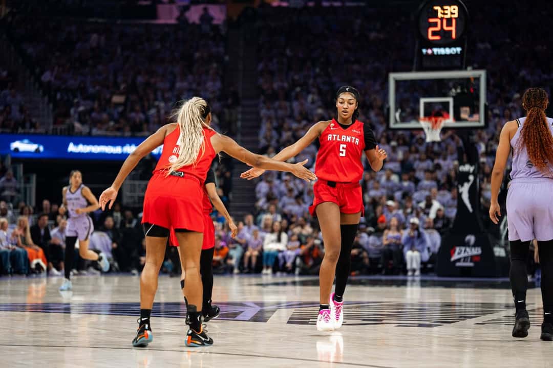 Angel Reese, con la camiseta roja número 5 del Atlanta Dream, espera la jugada en la cancha del Chase Center durante el Juego 1 de las Finales, con el público de las Valkyries detrás