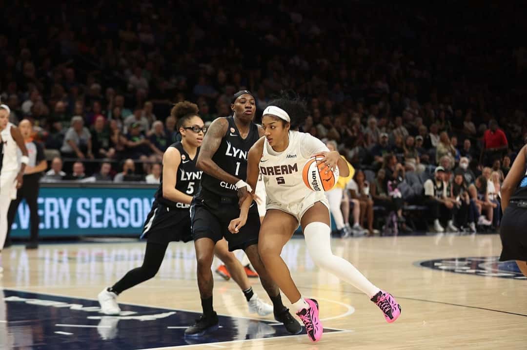 Foto de archivo: Angel Reese, del Atlanta Dream, con la camiseta blanca número 5, avanza con la pelota ante dos rivales de negro