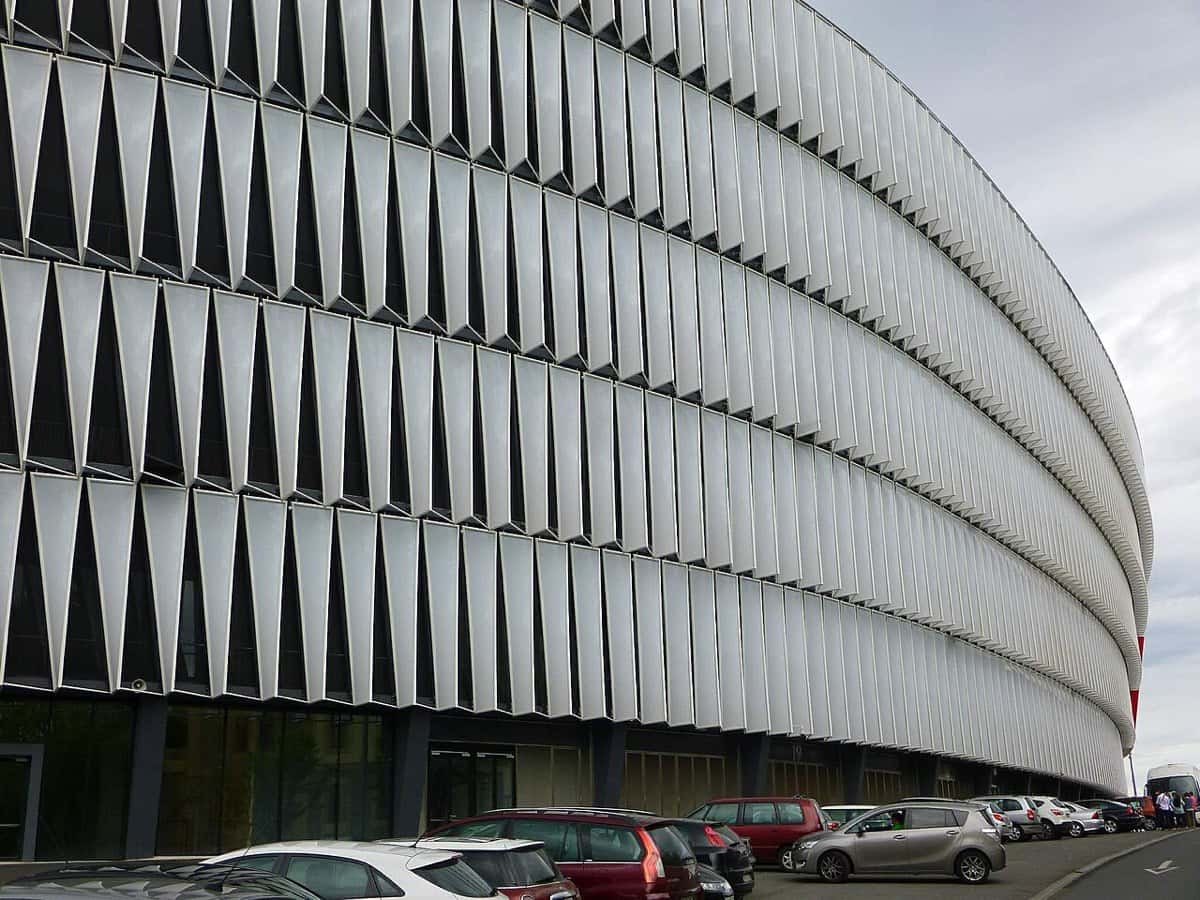 La fachada blanca de paneles curvos del estadio San Mamés, en Bilbao, vista desde la calle; foto de archivo de mayo de 2015 (foto: Zarateman, Wikimedia Commons, dominio público, CC0)