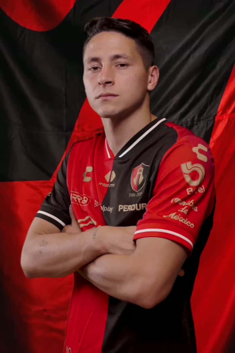 Florián Monzón posa de brazos cruzados con la camiseta rojinegra del Atlas, delante de una bandera roja y negra; foto oficial de archivo de la temporada 2026 (foto: Atlas FC)