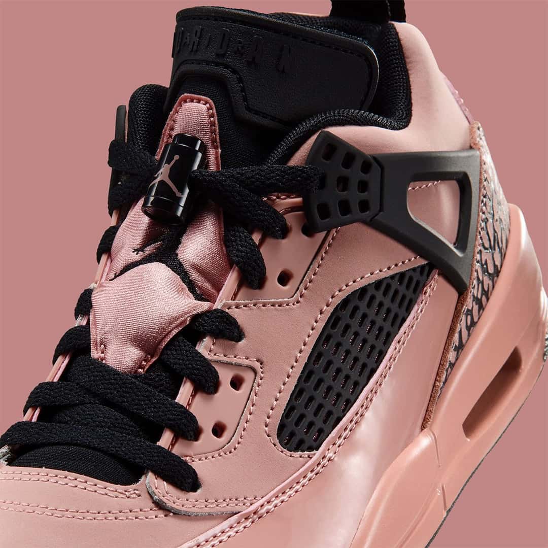 Detalle de la Jordan Spizike Low Rust Pink con la lengüeta satinada, el ala negra y los cordones negros sobre el charol rosa