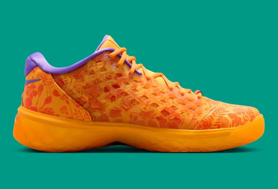 Lado interno del Nike Kobe 3 Low Protro Mamba Eterno sobre fondo verde agua, con estampado de flores y hojas en rojo y naranja debajo de la jaula, cuello violeta y suela naranja translúcida