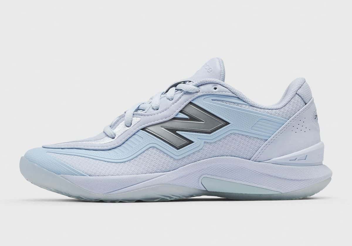 New Balance Kawhi V Oxford Blue de perfil, toda en celeste, con la N grande plateada en el costado y la suela celeste translúcida, sobre fondo gris claro