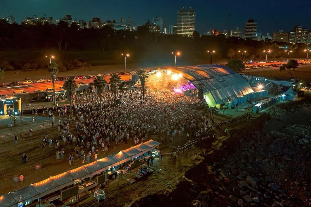 Vista nocturna desde lo alto de un show de Boris Brejcha al aire libre en Montevideo, con el público frente al escenario iluminado y la ciudad de fondo (foto de archivo, diciembre de 2021). Foto: Marcelo Campi, CC BY-SA 2.0, vía Wikimedia Commons