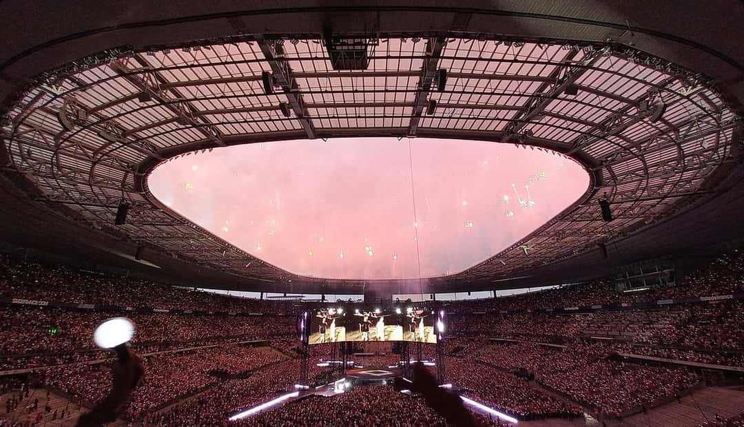 El escenario de la gira ARIRANG de BTS visto desde la tribuna del Stade de France de París, con el estadio lleno y fuegos artificiales en el cierre del show (foto de archivo, julio de 2026). Foto: Chiyako92, CC BY-SA 4.0, vía Wikimedia Commons