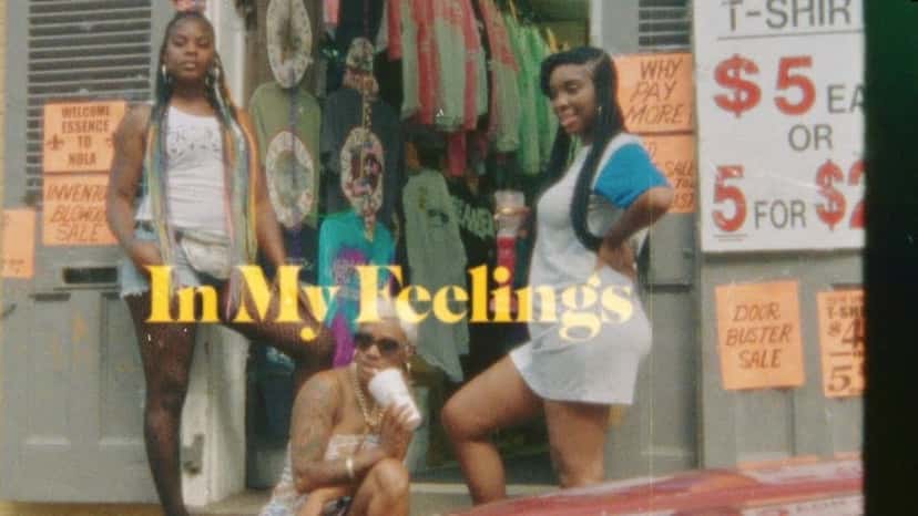 Fotograma del video oficial de «In My Feelings», de Drake: tres chicas posan frente a un local de remeras en Nueva Orleans, con el título del tema en letras amarillas
