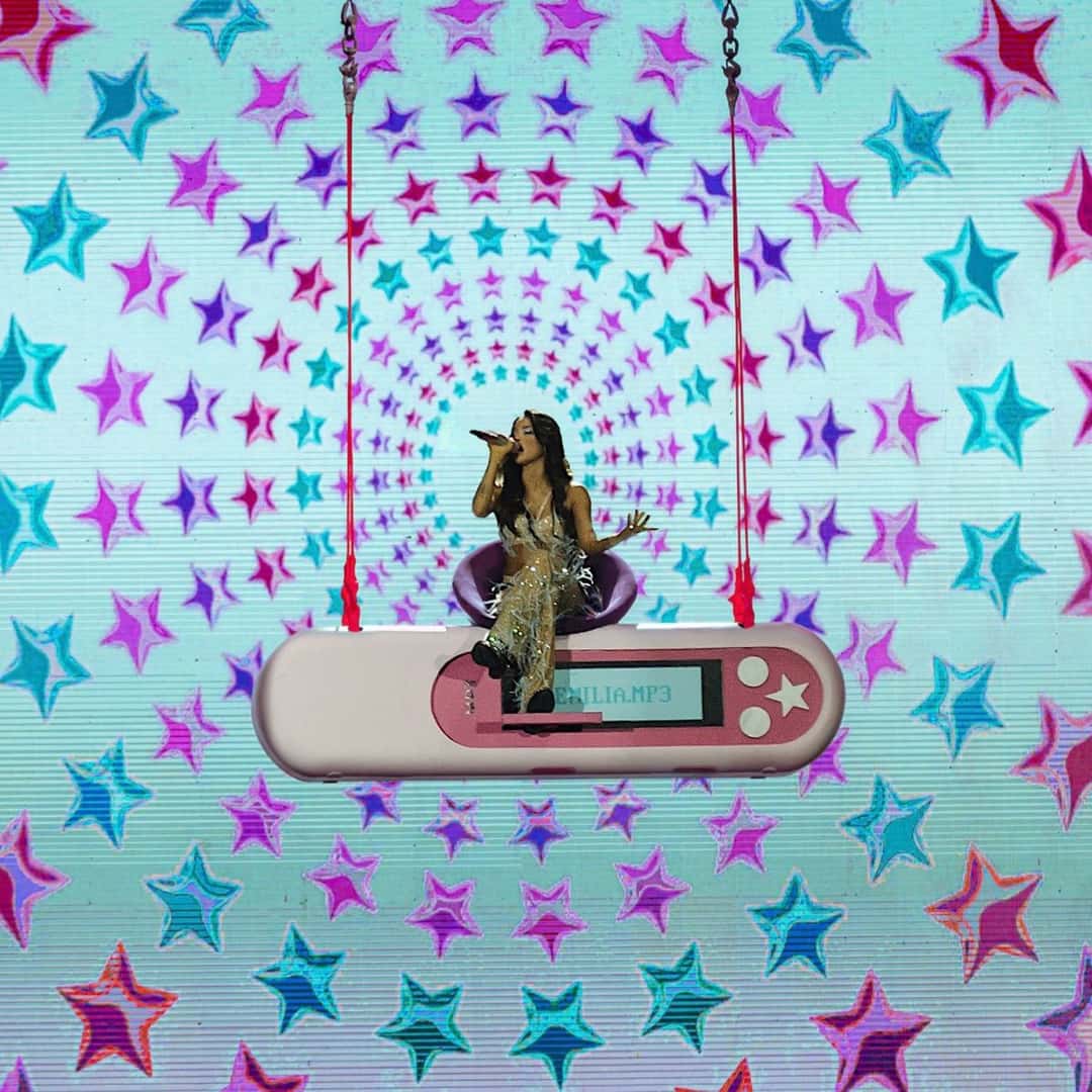 Emilia canta sentada sobre un reproductor de música gigante que cuelga de cadenas rojas, frente a una pantalla llena de estrellas de colores, en la portada de su disco en vivo «Tour_En_Vivo.mp3»