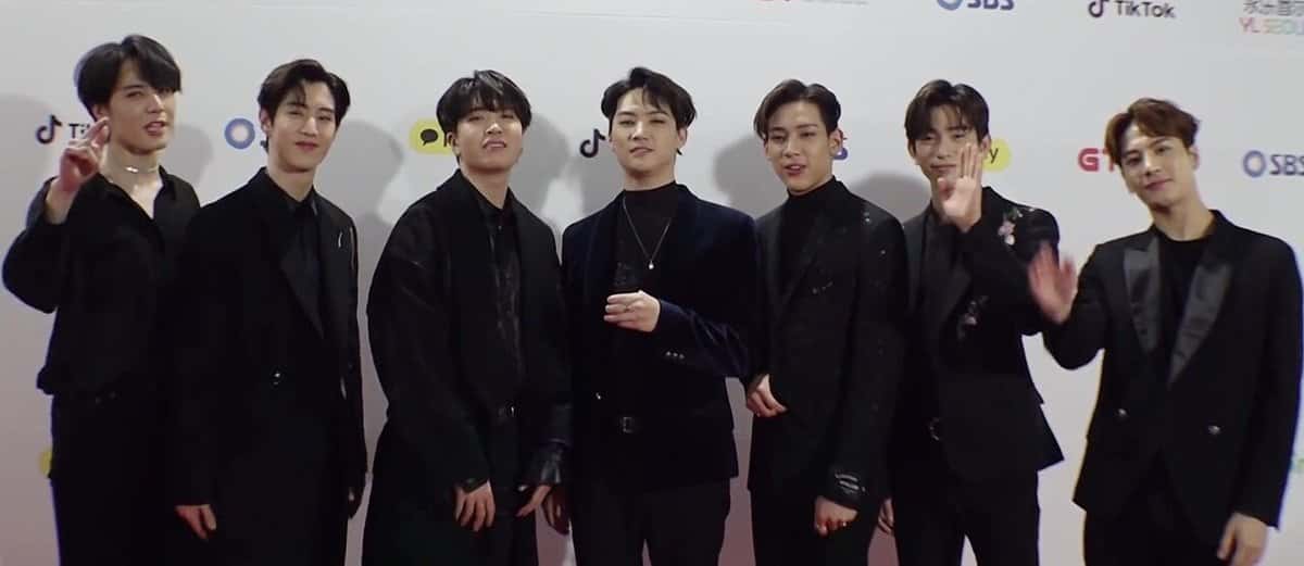 Los siete integrantes de GOT7, vestidos de negro, posan juntos y saludan a cámara en una alfombra roja (foto de archivo, enero de 2019)