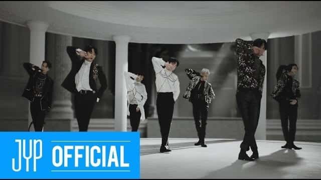 Imagen del video oficial de «NOT BY THE MOON»: los integrantes de GOT7 bailan en blanco y negro entre columnas, con trajes oscuros y camisas blancas, con el logo de JYP Official en la esquina. Imagen: JYP Entertainment