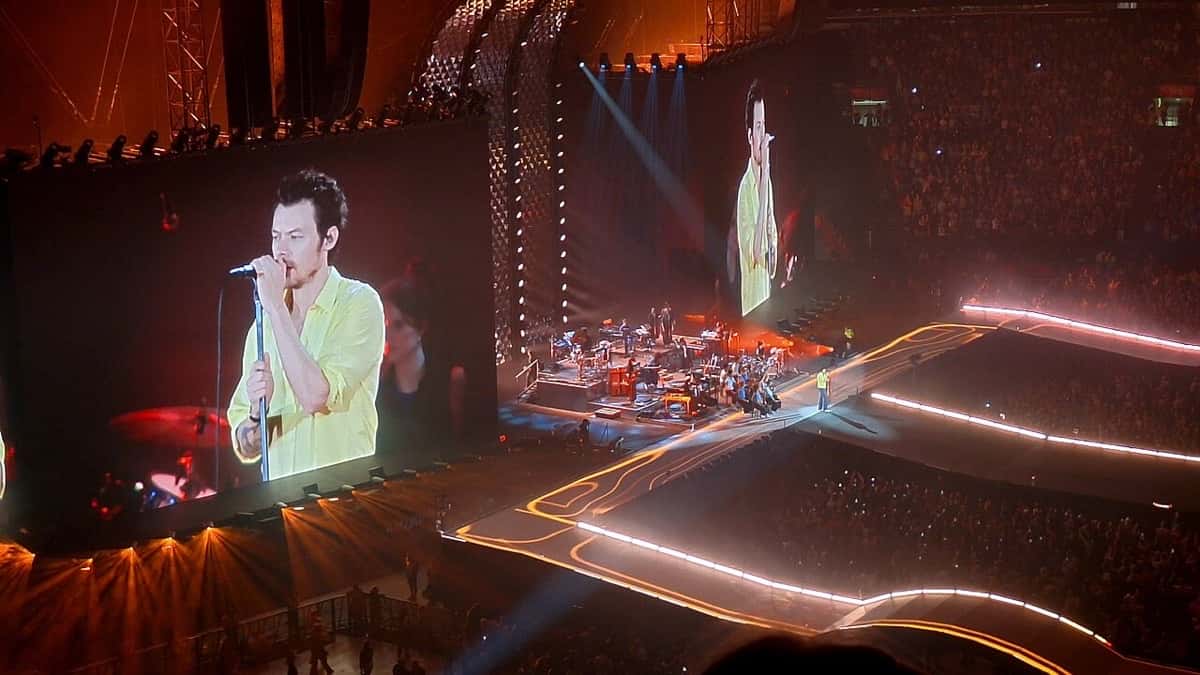 Harry Styles canta con camisa amarilla en las pantallas gigantes de un estadio techado, durante un show de su gira Together, Together en Ámsterdam (foto de archivo, mayo de 2026)