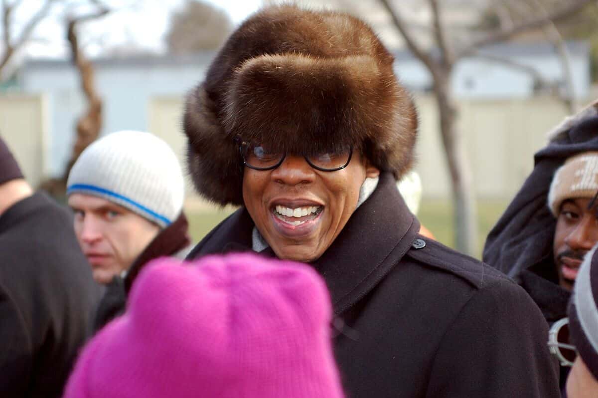 Jay-Z sonríe con gorro de piel, anteojos y abrigo oscuro, rodeado de gente al aire libre, en noviembre de 2010 (foto de archivo)