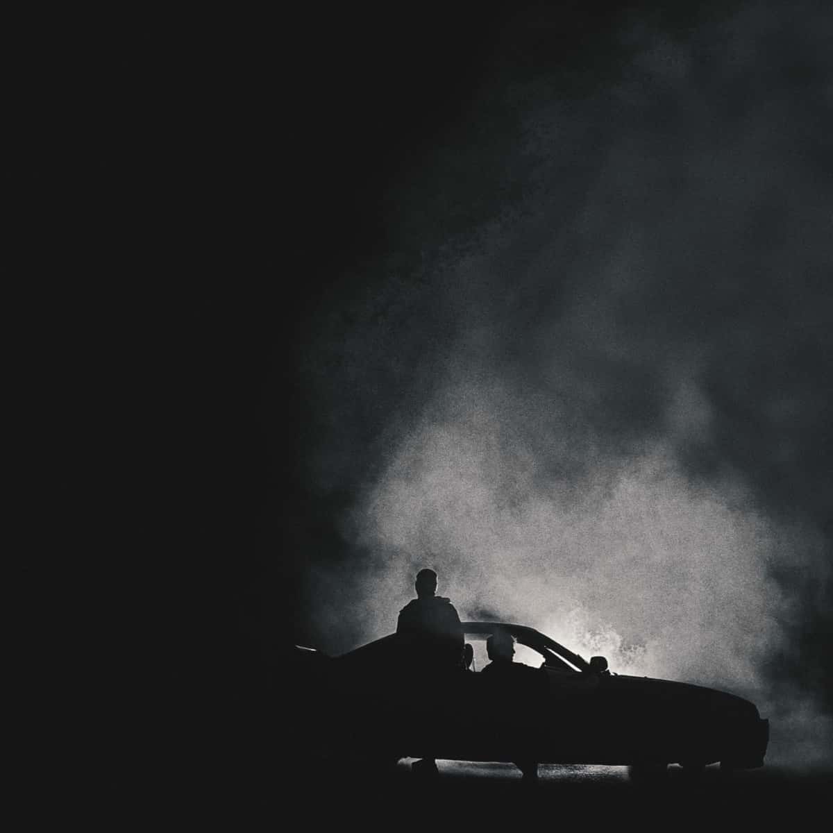 Portada de «DOGGY», de La Pantera y Quevedo: siluetas de personas sobre un auto en la oscuridad, con una nube de humo blanco iluminada detrás