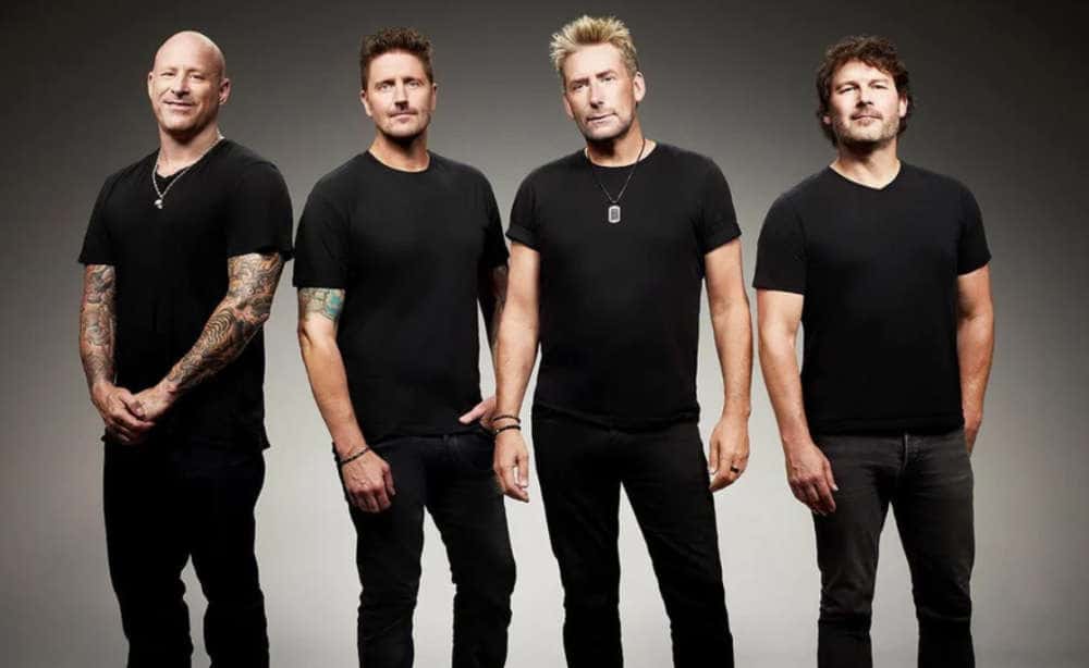 Los cuatro integrantes de Nickelback, con remeras negras, posan de pie y de frente sobre un fondo gris, en una foto de prensa oficial