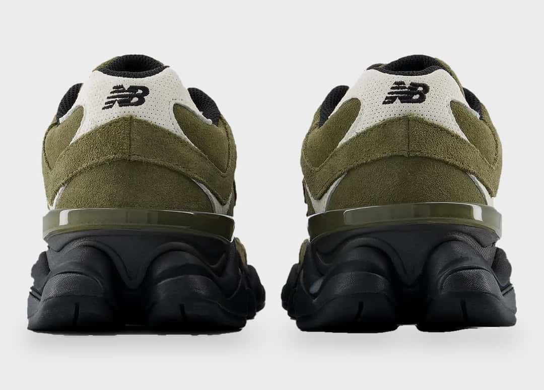 Vista trasera del par del New Balance 9060 Trail verde oliva sobre fondo gris claro, con el logo NB negro sobre un panel blanco en el talón, gamuza verde a los costados y la suela negra con su forma ondulada