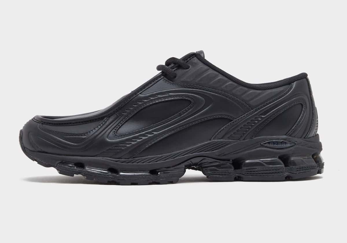 New Balance 1890A Black Leather en cuero negro con puntera de mocasín y suela gruesa negra, de perfil sobre fondo gris claro