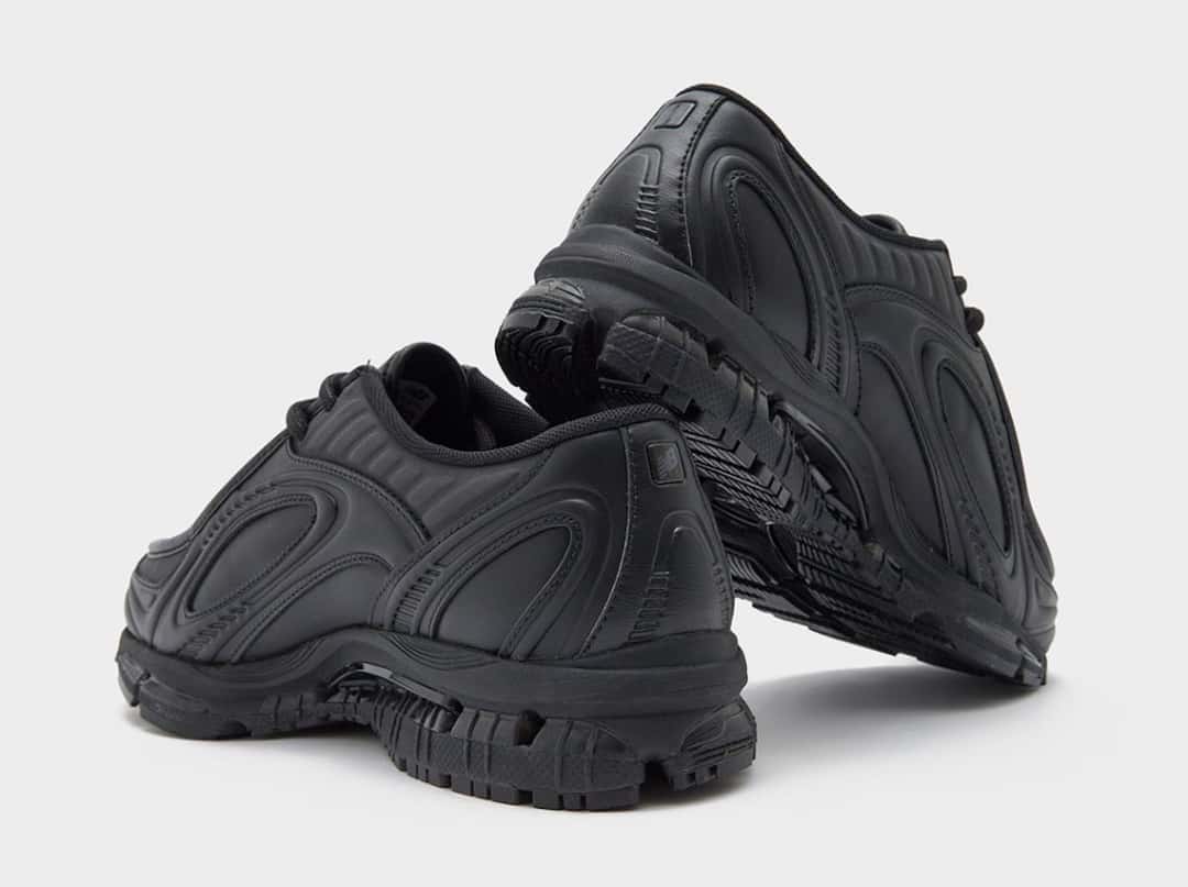 Par de New Balance 1890A Black Leather visto desde atrás, con la suela gruesa segmentada y el logo chico en el talón