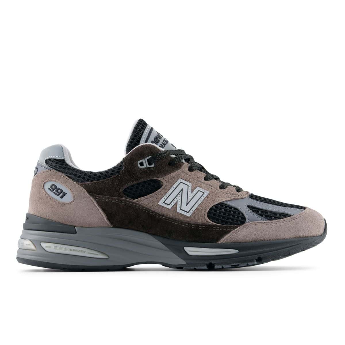 New Balance 991v2 Made in UK Iron/Mulch de perfil, con gamuza marrón en dos tonos, malla negra y N gris claro, sobre fondo blanco